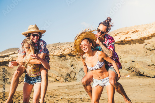 Laughing a lot group of people enjoying and playing at the beach in summer holday vacation outdoor - alternative millennial have fun in friendship together in sunny day outdoor lifestyle