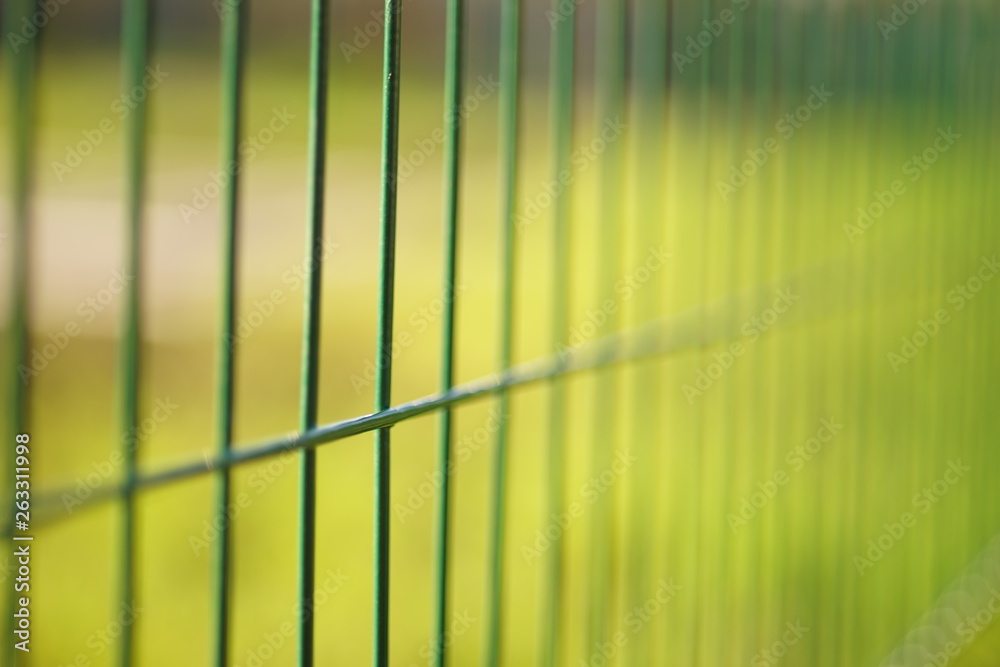 grid of green fence mesh on the background of the lawn field