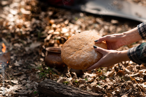 Closeup of fresh rustsic bread in a woman's hand. The background of the forest photo