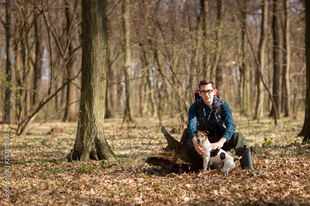 Young man with backpack hiking in the forest with his dog. Nature and physical exercise concept Young man with backpack hiking in the forest with his dog. Nature and physical exercise concept