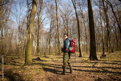 Young man with backpack hiking in the forest. Nature and physical exercise concept