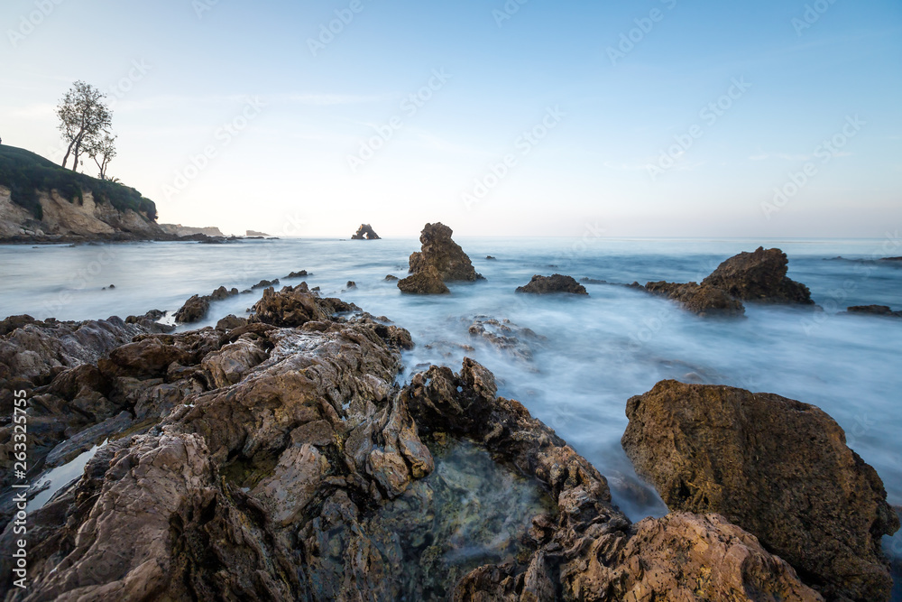 Long exposure fluffy ocean mists rush over tidal pool rocks at the beach Long exposure fluffy ocean mists rush over tidal pool rocks at the beach