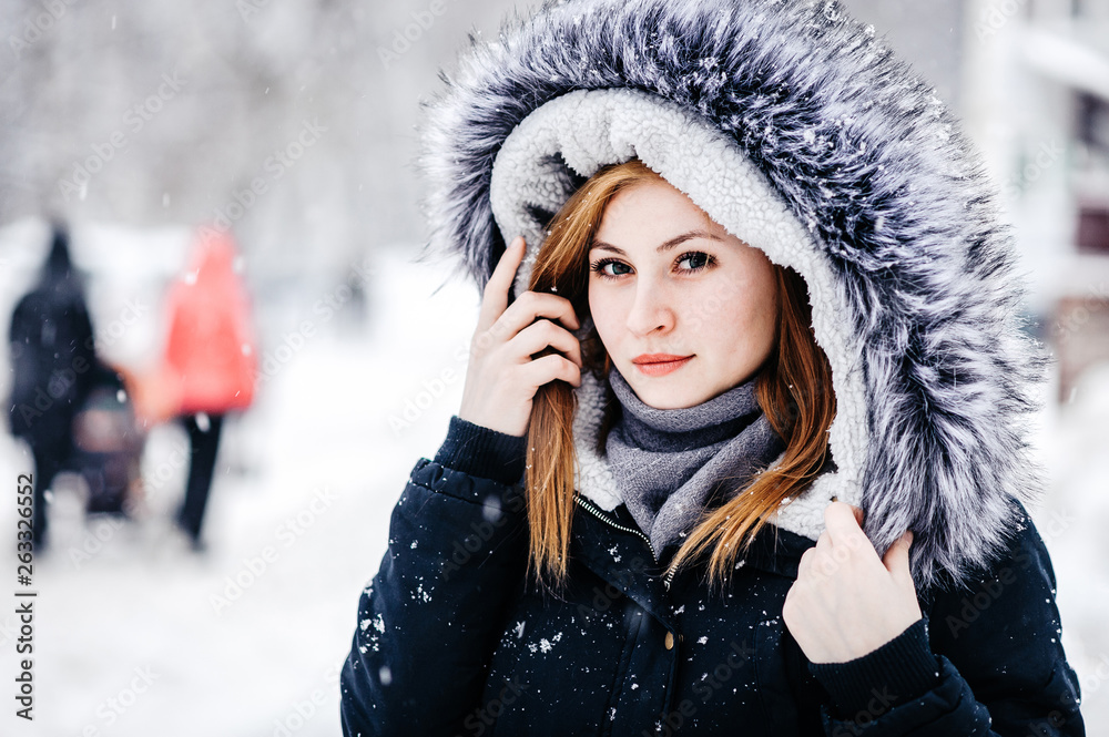 Outdoor portrait of young beautiful girl wearing in black jacket with a hood . Model posing in street. Winter holidays concept. Outdoor portrait of young beautiful girl wearing in black jacket with a hood . Model posing in street. Winter holidays concept.