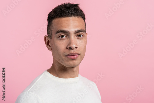 Closeup half-turn face portrait of man posing in the studio against a pink background.- Image