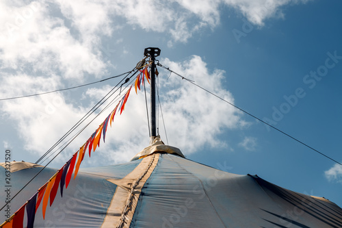 Column of blue circus tent with colorful pennants and sunlight