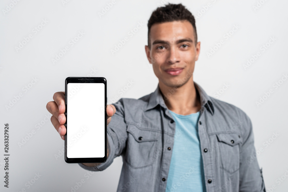 Focus on the smartphone with white screen which a man holding  in his hand. Mockup