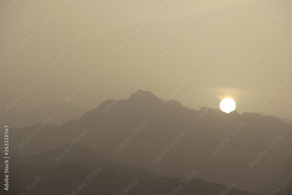 sunset in the misty haze on a background of mountains
