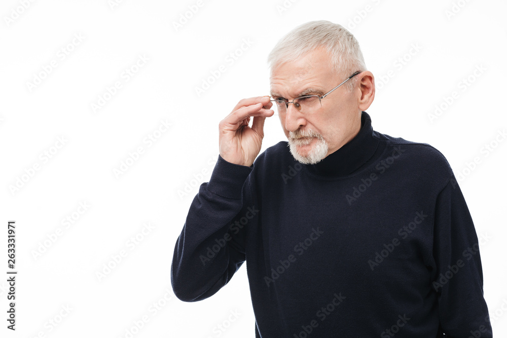 Old attractive man with gray hair and beard in eyeglasses and black sweater thoughtfully looking aside over white background isolated Old attractive man with gray hair and beard in eyeglasses and black sweater thoughtfully looking aside over white background isolated
