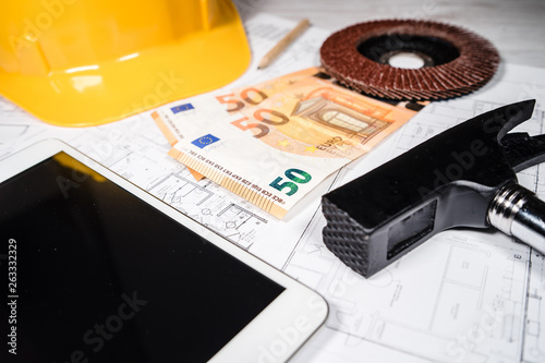 Construction industry costs money euro banknotes by tools safety equipment and blueprints