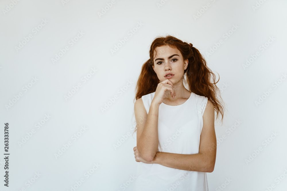 Pensive red-haired girl with ponytails on a white background. School clothes, student Pensive red-haired girl with ponytails on a white background. School clothes, student