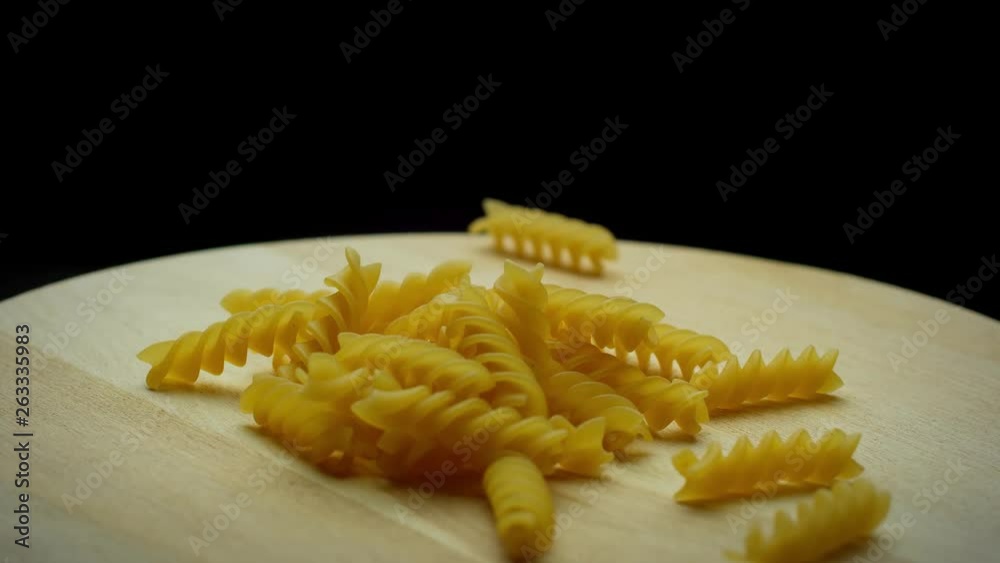 Spiral pasta rotates on a wooden board; closeup shot. Spiral pasta rotates on a wooden board; closeup shot.
