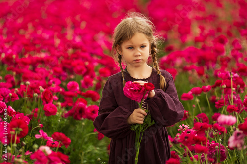 girl in a cherry dress and pigtails collects bright pink flowers photo
