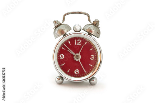 Steel vintage rusty alarm clock with red design close-up isolated on white background. The clock shows eight to one.