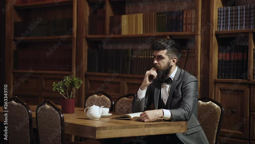 Portrait of man reading book in library on the old wooden table in ancient style in the library cabinet. Intelligent men, scientists spend leisure in library. Intelligent elite and education concept. Portrait of man reading book in library on the old wooden table in ancient style in the library cabinet. Intelligent men, scientists spend leisure in library. Intelligent elite and education concept.