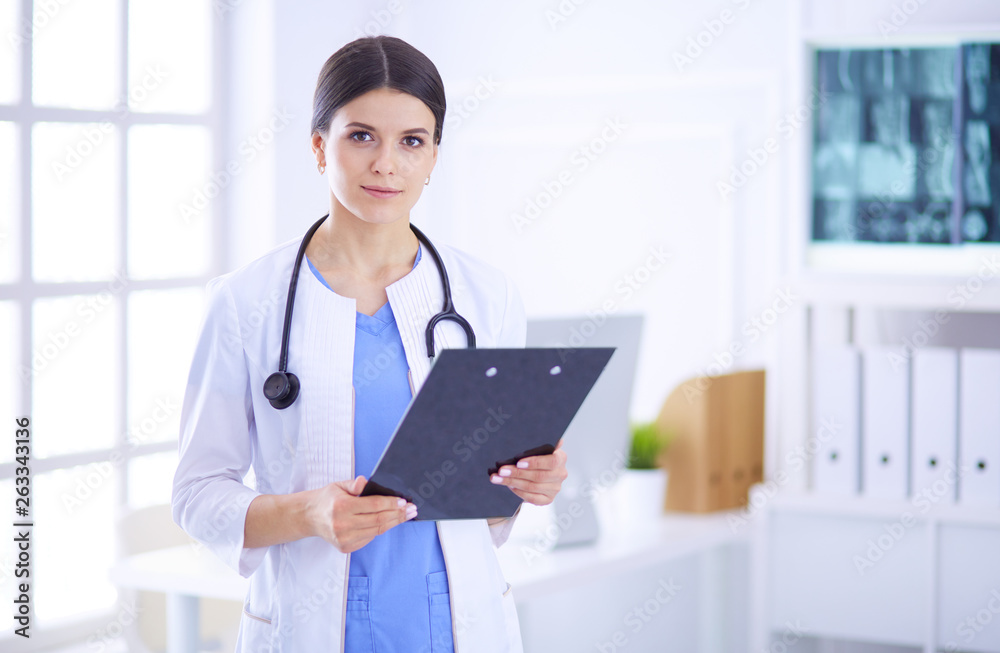 Young smiling female doctor with stethoscope holding a folder at doctor's office Young smiling female doctor with stethoscope holding a folder at doctor's office