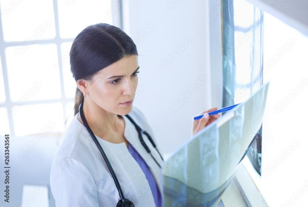 Young female doctor with stethoscope examining X-ray at doctor's office Young female doctor with stethoscope examining X-ray at doctor's office