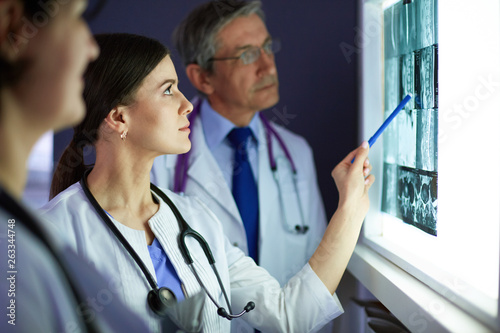 Group of doctors examining x-rays in a clinic, thinking of a diagnosis