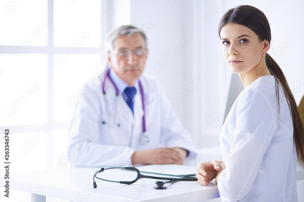 A doctor looking at the camera with her male colleage in the back of the conference room in hospital A doctor looking at the camera with her male colleage in the back of the conference room in hospital