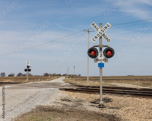 railroad crossing with warning sign and lights in countryside with a gravel road Fototapet