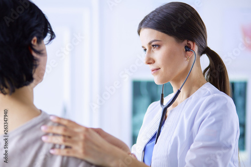 A female doctor listening a patient with a stethoscope