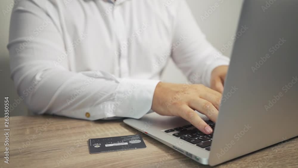 Shopping online concept. man hands holding credit card and using laptop. credit card is on the table Shopping online concept. man hands holding credit card and using laptop. credit card is on the table