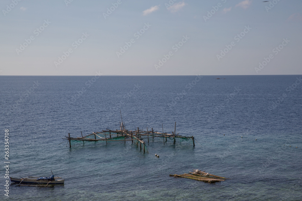Fish trap fisherboat and float at the blue sea with sun shine white clouds and a blue sky a rural tranquil sea scape scene