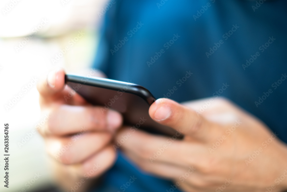 Close-up of a man's hand holding and using a mobile phone. Subject is blur Close-up of a man's hand holding and using a mobile phone. Subject is blur