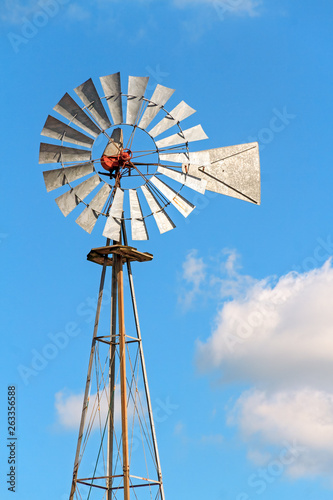 Windmill and Sky - A retro metal windmill stands tall against a cloudy blue sky in Indiana.
