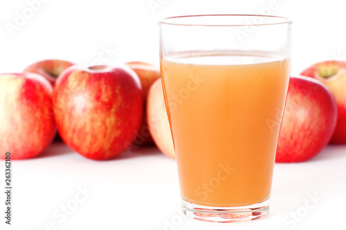 Glass of Apple Juice with Red Apples Behind Glass Isolated
