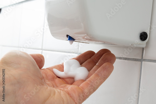 Liquid Soap Dispenser On Wall For Hand Cleaning photo