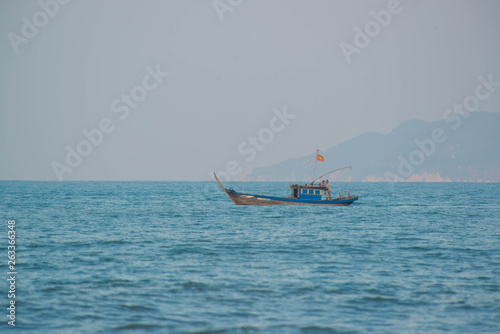 A beach in Hoi An with tourists, boats and fisherman, Vietnam.