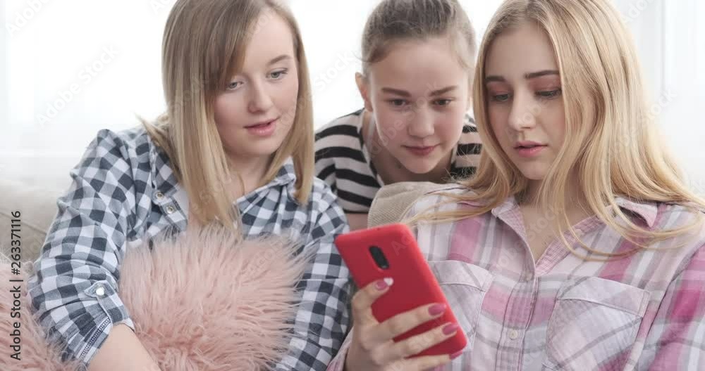 Teenage girls reading social media content on mobile phone