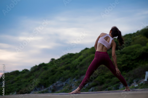 Rear view of healthy women practicing standing and stretching pose. standing twisting pose. yoga landscape on evening view on evening nature evening outdoor, concept for exercising, health care