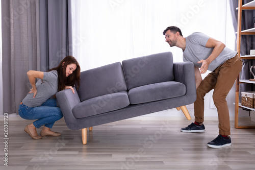 Woman Suffering From Back Pain While Lifting Sofa