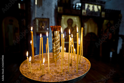 Round candlestick with burning candles in the interior of russian orthodox church. Candles under the ancient icon framed with the gold. Сelebration of holy holidays photo