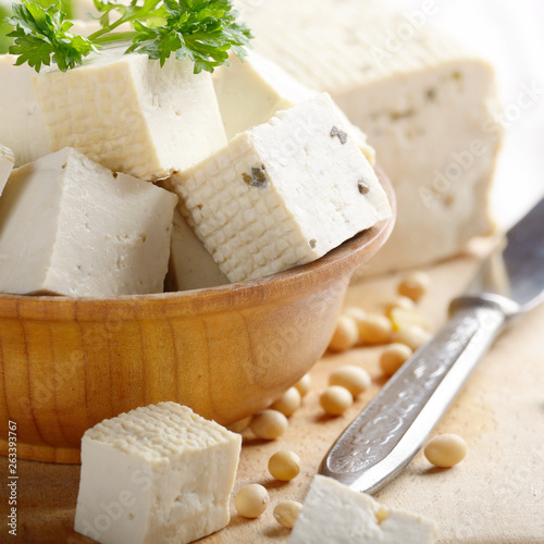 Soy Bean curd tofu in wooden bowl on white wooden kitchen table. Non-dairy alternative substitute for cheese. Place for text photo