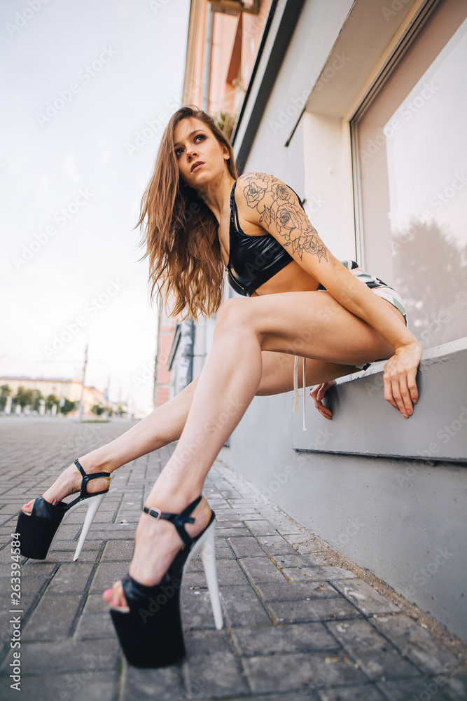 Girl in high heels posing among the streets of the city. Girl in a black top and short shorts. Girl in high heels posing among the streets of the city. Girl in a black top and short shorts.