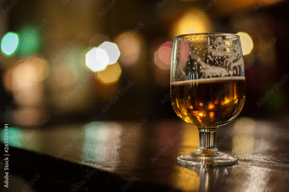 Beer Glass with backlight in the evening on outdoor table top.Bright colourful bokeh in background.Seville,Spain Beer Glass with backlight in the evening on outdoor table top.Bright colourful bokeh in background.Seville,Spain