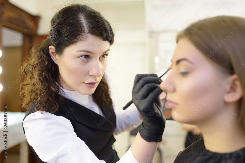 Beautician applying the tone of the foundation using special brush on face young beautiful model. Facial care and make up Beautician applying the tone of the foundation using special brush on face young beautiful model. Facial care and make up