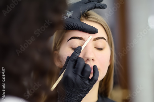 Cosmetologist making eyebrows design. Attractive woman getting facial care at beauty salon. Architecture eyebrows.