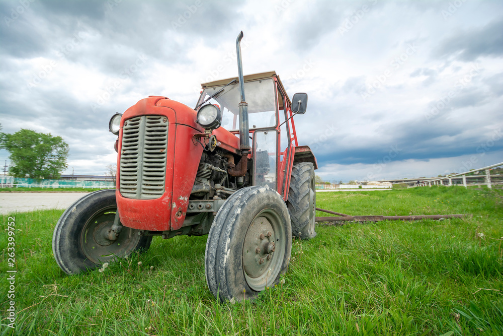 An old and abandoned tractor sitting in the field, broken and unused An old and abandoned tractor sitting in the field, broken and unused