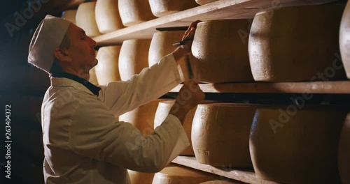 Slow motion close up of a cheesemaker is controlling the seasoning of Parmesan cheese, which was maturing by ancient Italian tradition for many months. photo