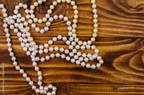 Pearl necklace on wooden background. Top view