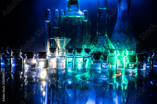 Pharmacy and chemistry theme. Test glass flask with solution in research laboratory. Science and medical background. Laboratory test tubes on dark toned background