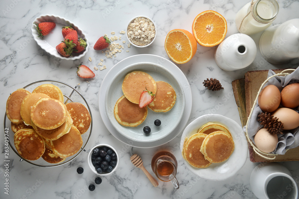 A stack of pancake with blueberries, strawberries, orange on white marble table. Breakfast menu, top view A stack of pancake with blueberries, strawberries, orange on white marble table. Breakfast menu, top view