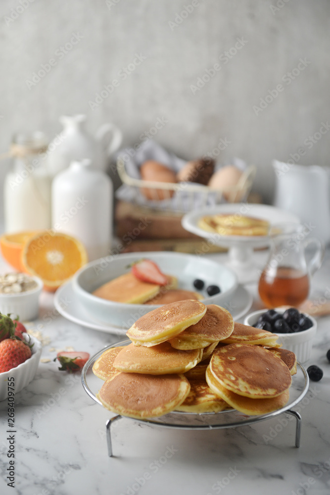 A stack of pancake with blueberries, strawberries, orange on white marble table. Breakfast menu, top view A stack of pancake with blueberries, strawberries, orange on white marble table. Breakfast menu, top view