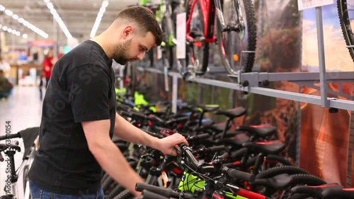 Handsome man is looking to buy new bicycle in the store. Sportsman wants to buy new mountain bike.
