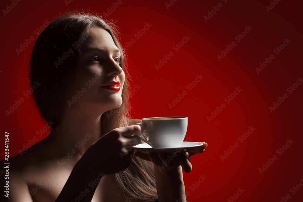 Attractive lady brunette with pleasure holding a empty cup in hand in studio at the red background Attractive lady brunette with pleasure holding a empty cup in hand in studio at the red background