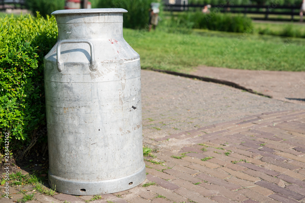 close up milk churn against hedge in Dutch street close up milk churn against hedge in Dutch street