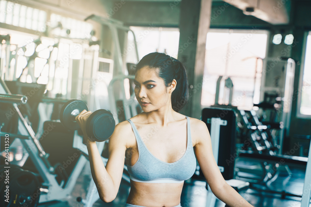 Obraz premium Wellbeing smart asian sport women lifting dumbbell in gym